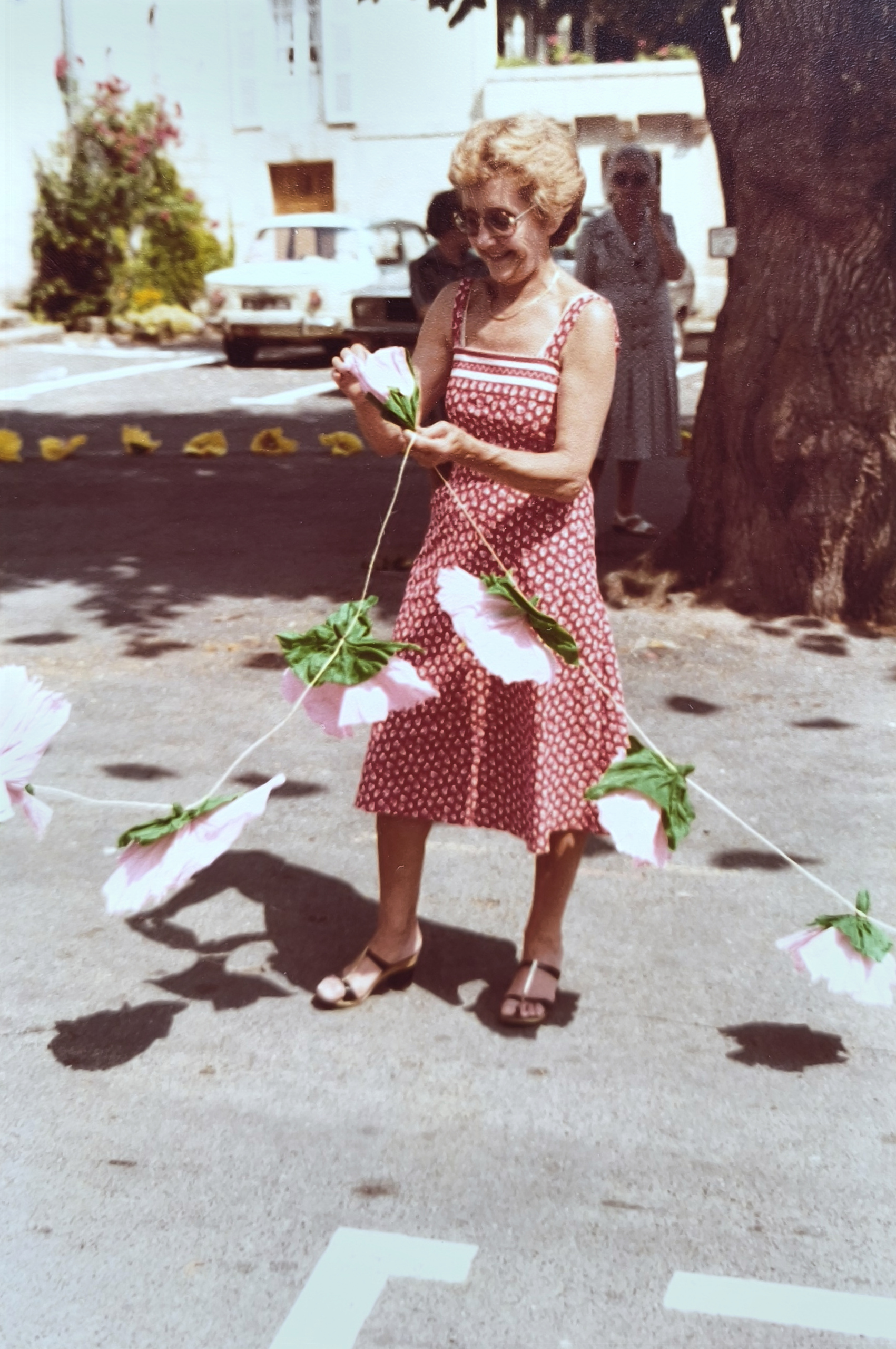 Félibrée 1979 — Femme en robe rouge parmi les fleurs de papier